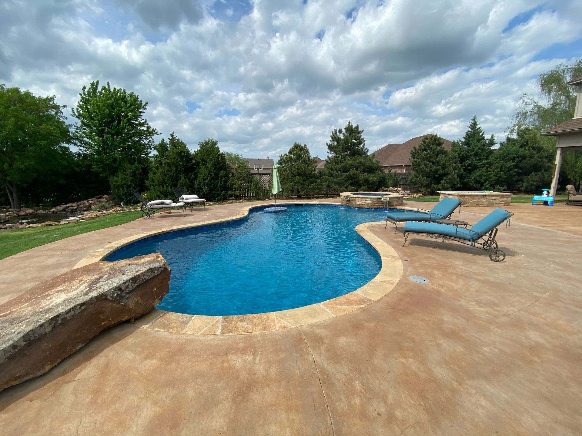 a large swimming pool surrounded by chairs and umbrellas in a backyard