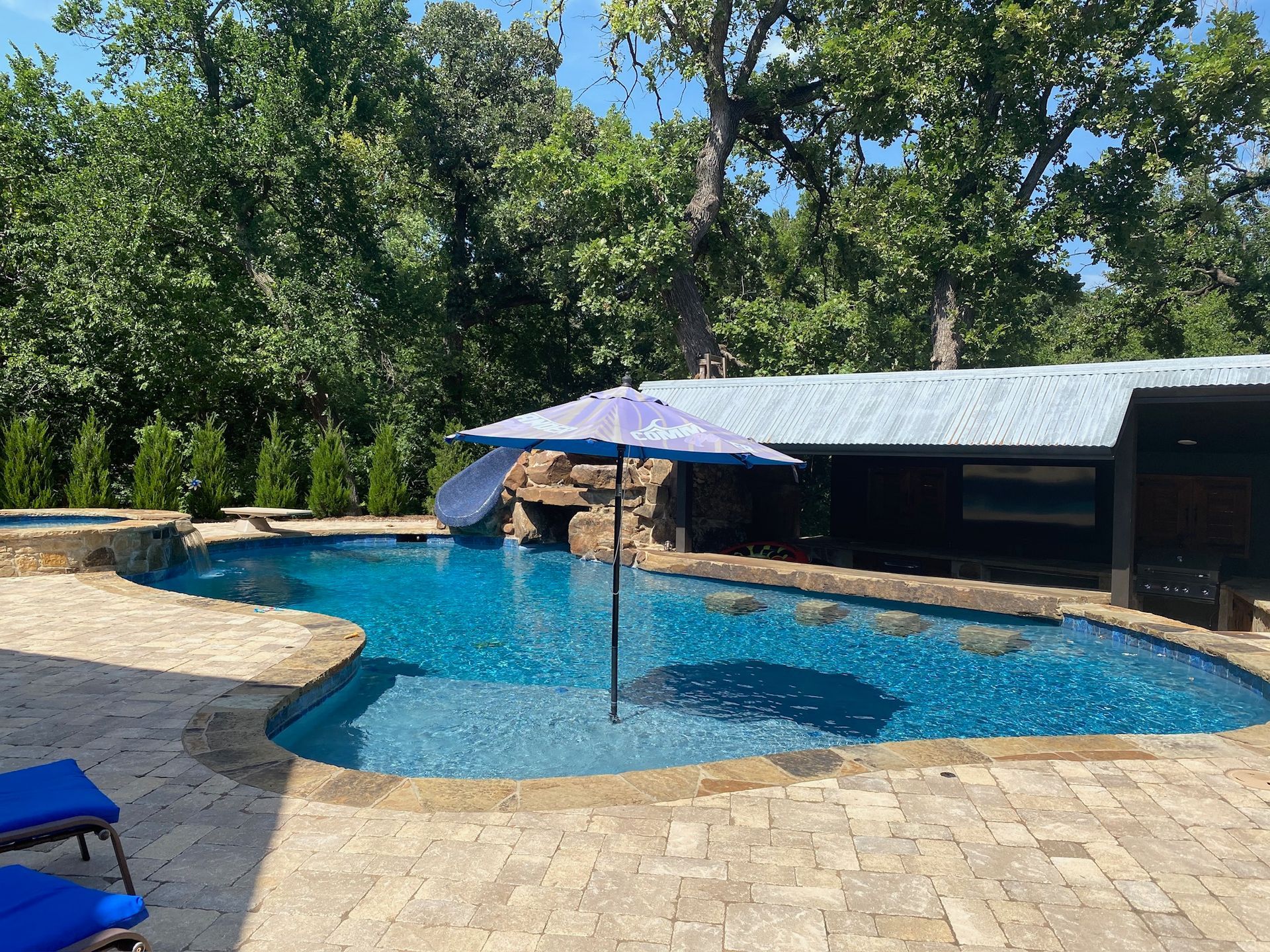 a large swimming pool with a purple umbrella in the middle