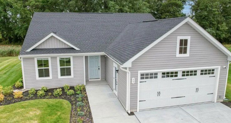 Gray house with white trim, front door, garage, and garden.