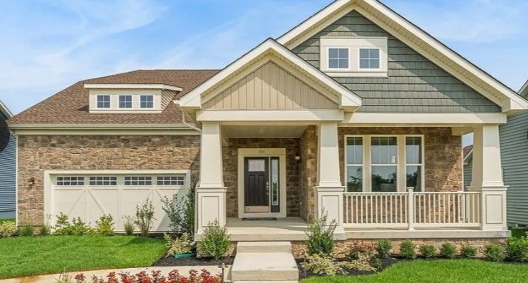 A single-family home with brick and shingle exterior, porch, and garage, in a landscaped setting.