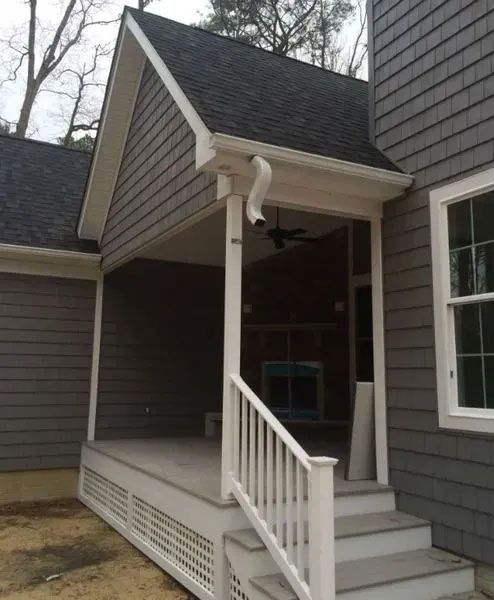 Covered porch with gray siding, white railings, and steps.