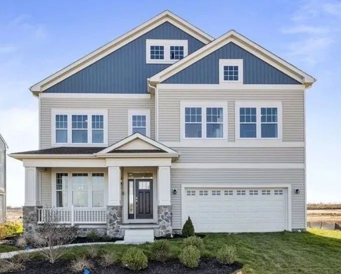 Two-story house with blue and gray siding, white trim, and a two-car garage under a blue sky.