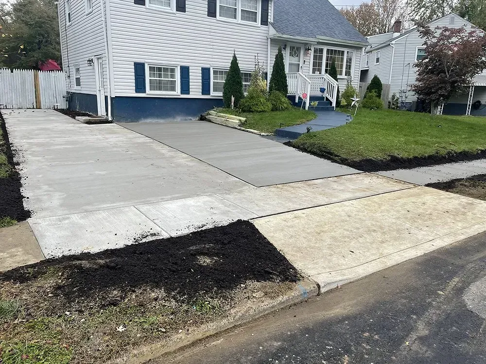 Suburban house with a concrete driveway, front lawn, and a black patch of landscaping at the curb