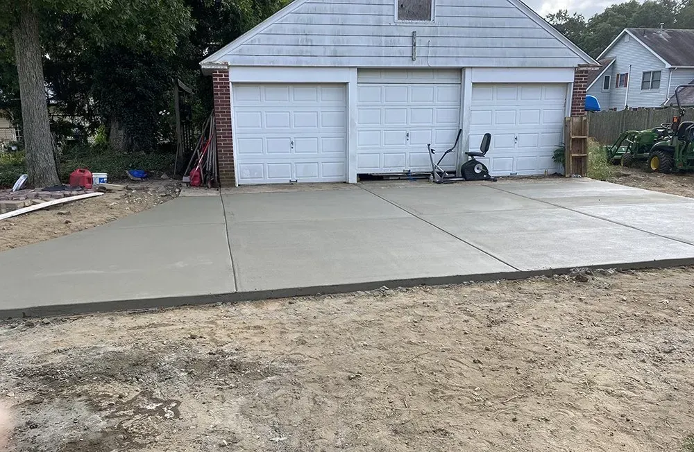 Driveway in front of a two-car garage with a scooter parked near the center door.