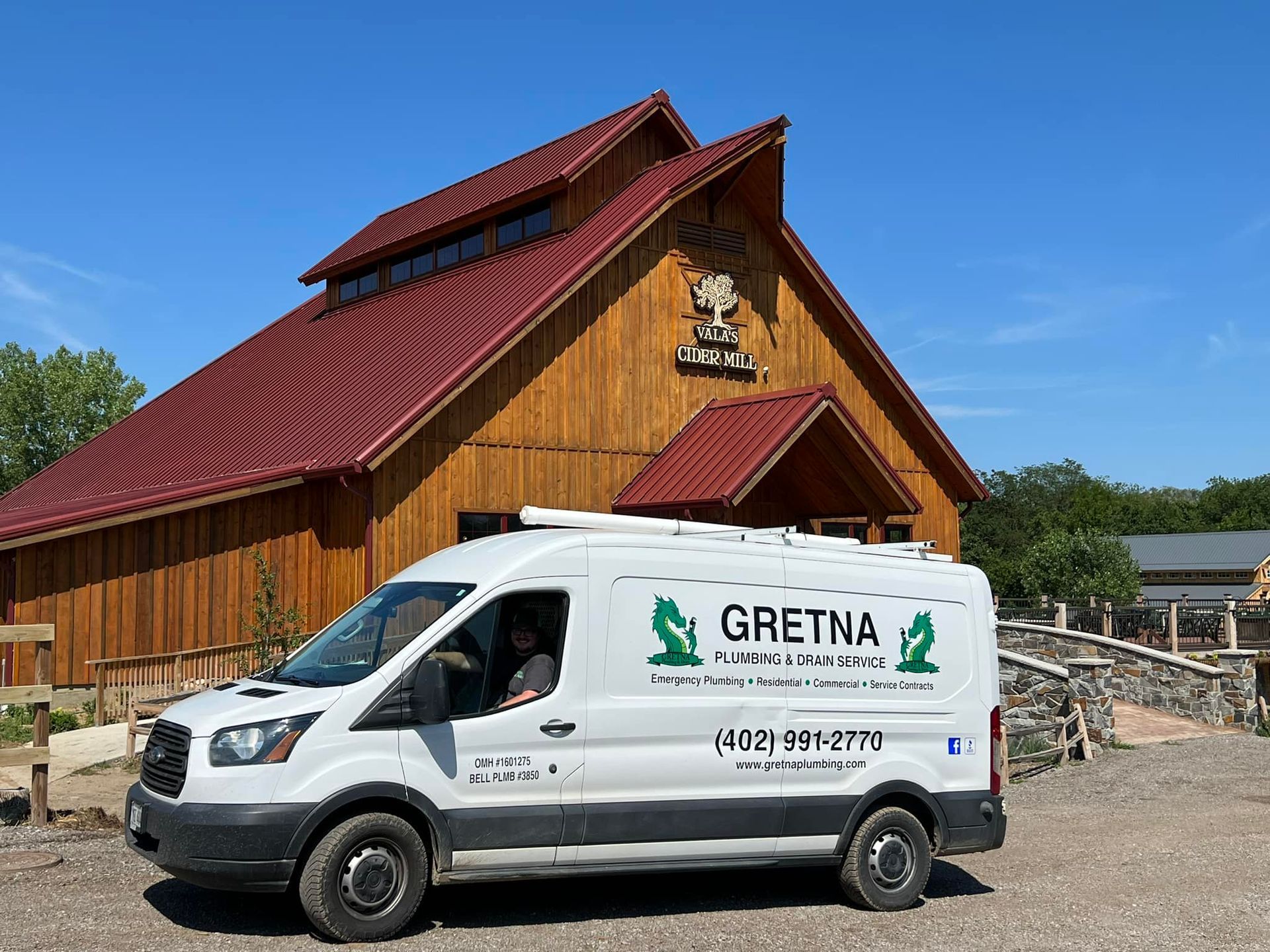 White van with Gretna logo parked in front of a wooden building with red roof.