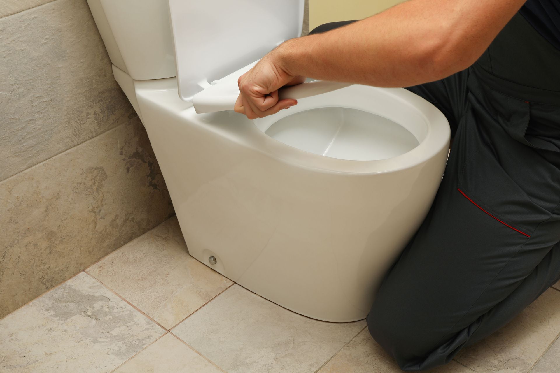 Person installing a white toilet seat in a bathroom.