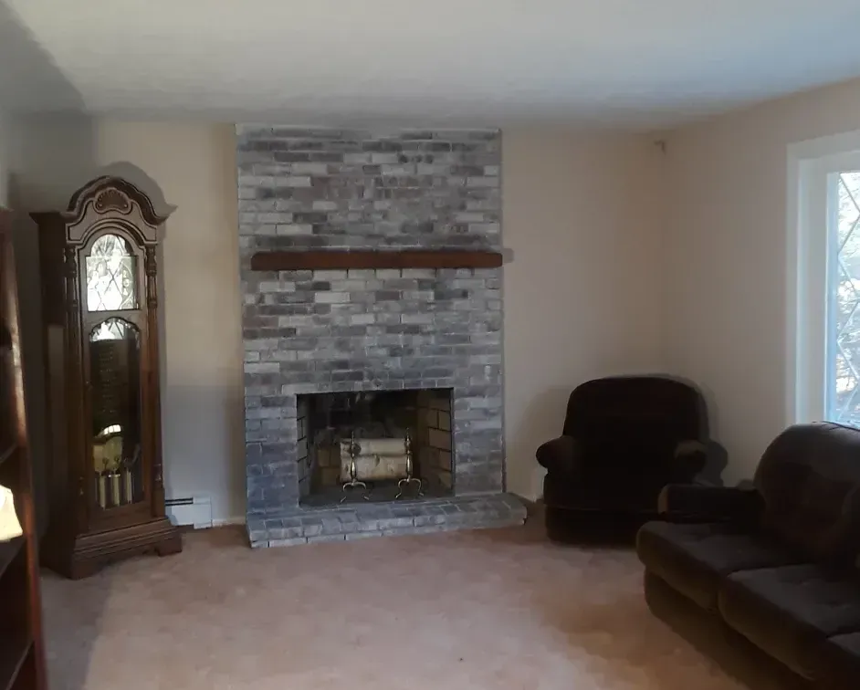a living room with a fireplace , couch , chair and grandfather clock .