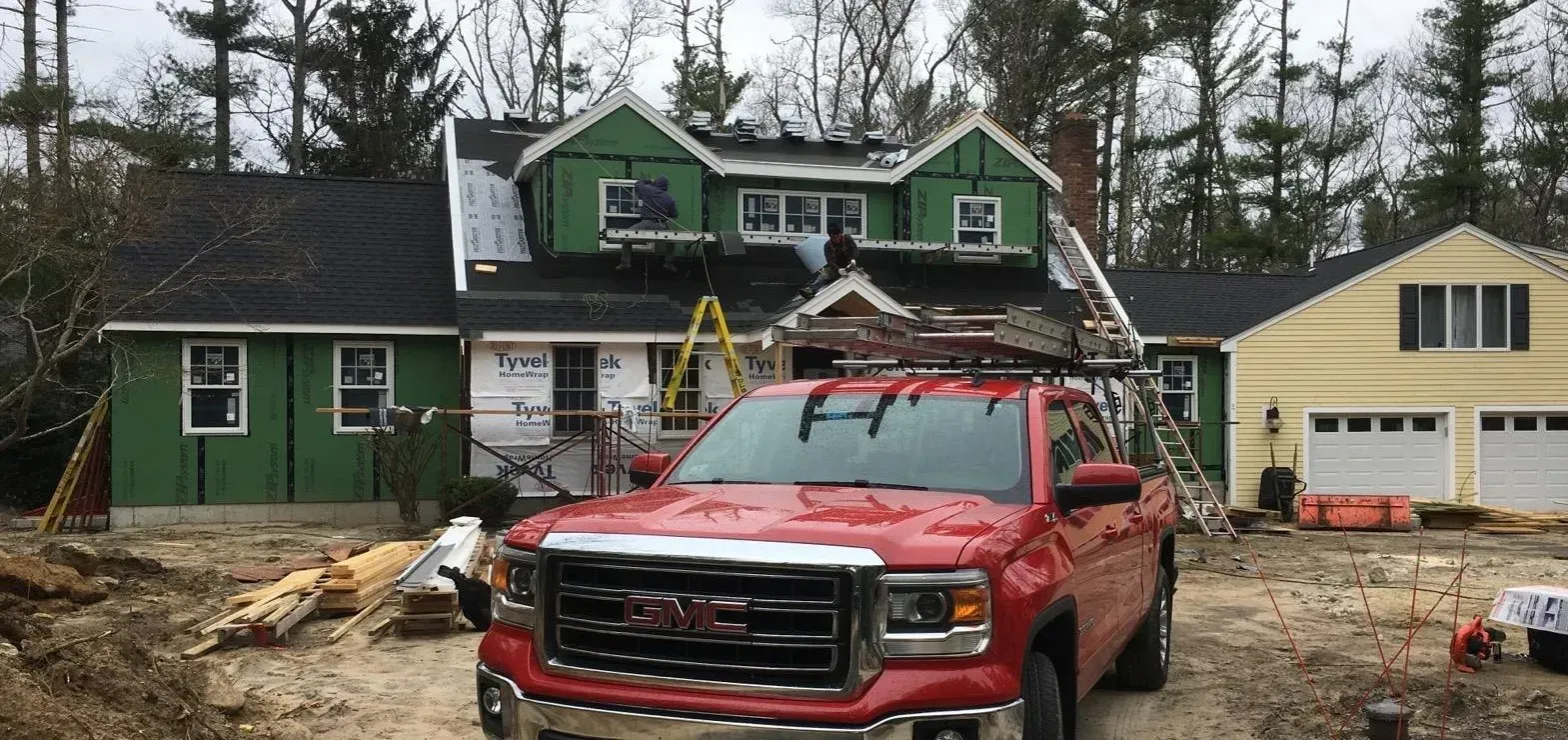 a red truck is parked in front of a house under construction .