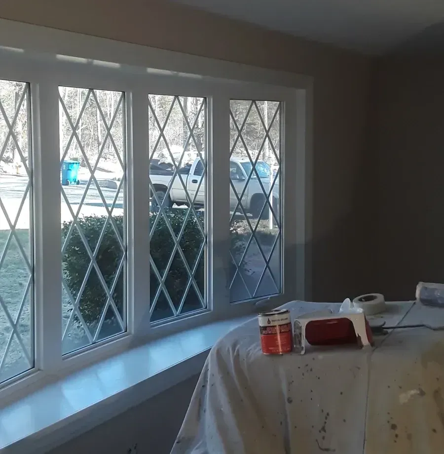 a room with a lot of windows and a table with a can of paint on it