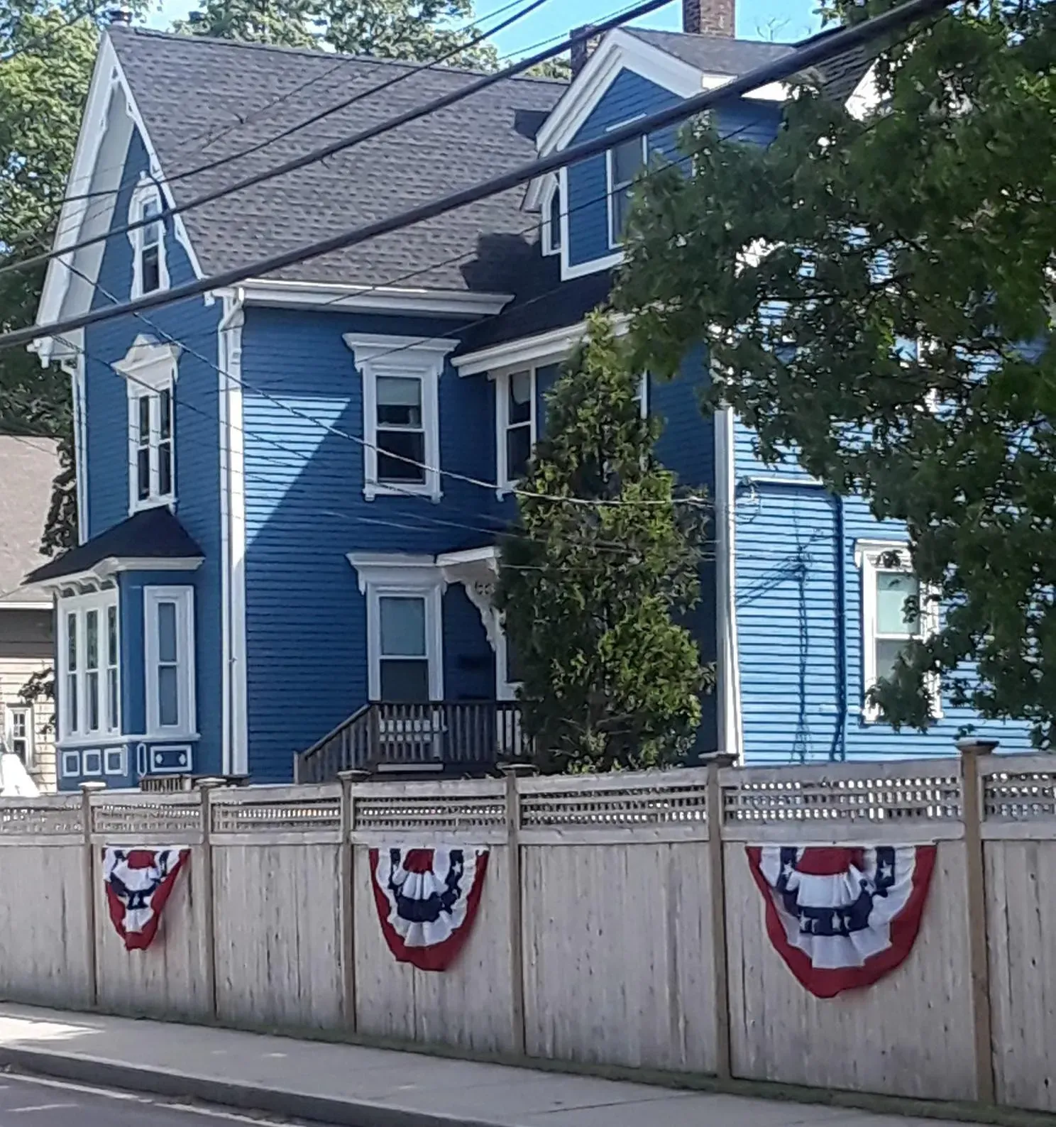 a blue house is behind a wooden fence with american flags on it