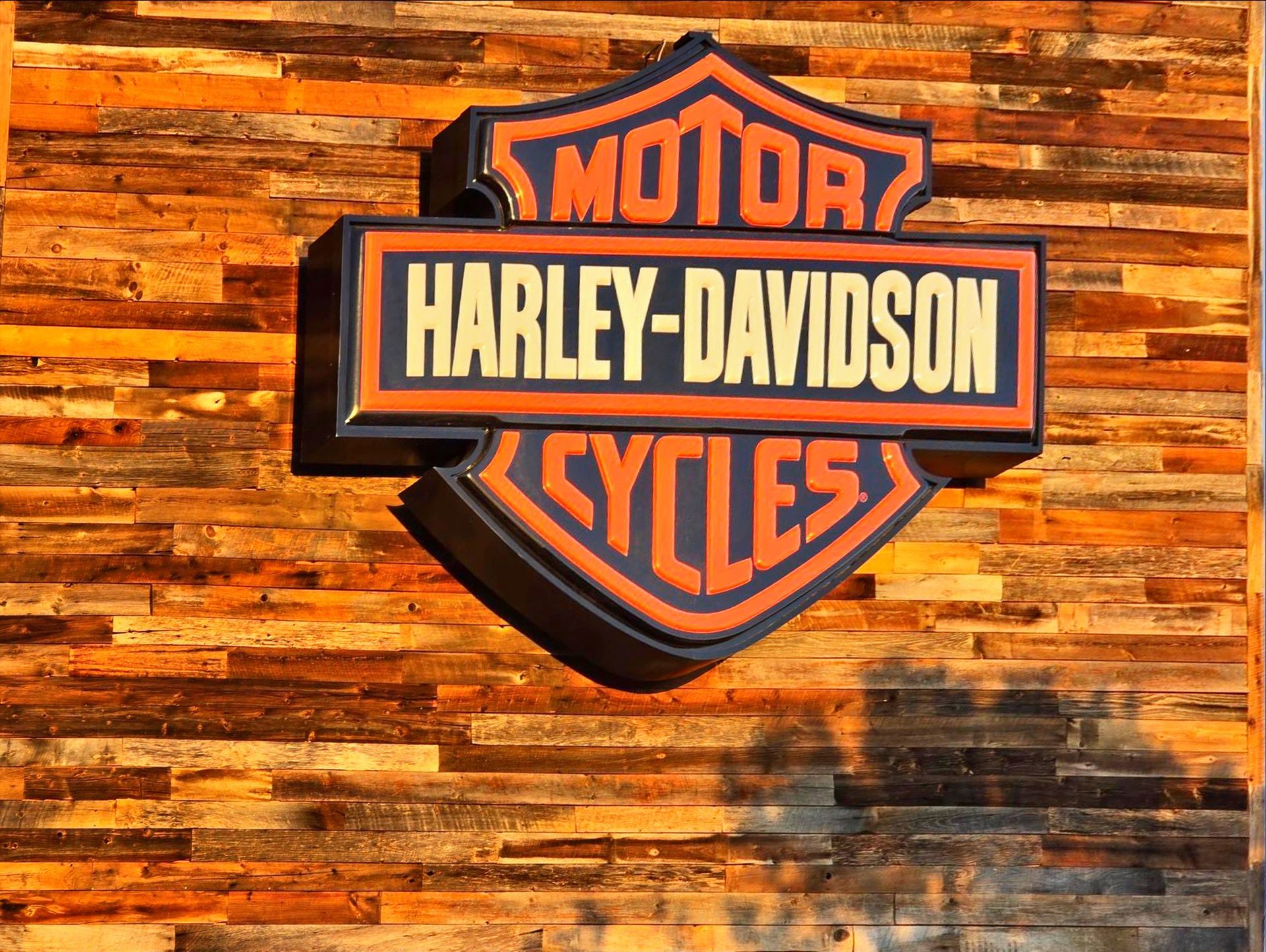 Harley-Davidson sign on a rustic wood background.