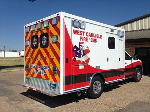 An ambulance from west carlisle fire and ems is parked in front of a building.