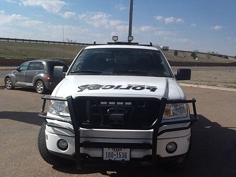 A white police truck is parked in a parking lot