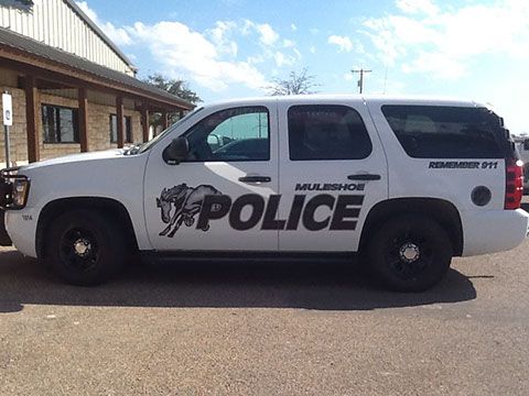 A white police suv is parked in front of a building.