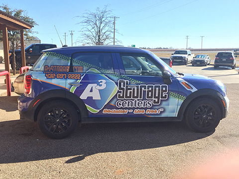 A blue car with a wrap that says savage centers