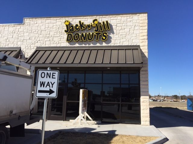 A one way sign is in front of a donut shop