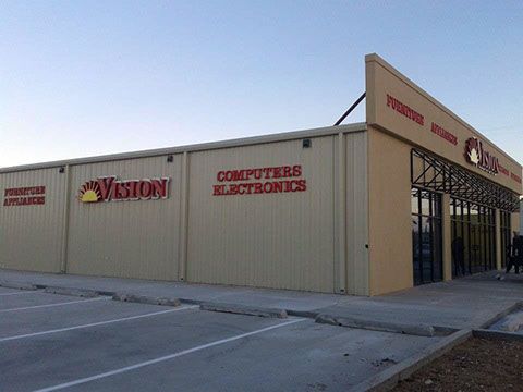 A vision computer and electronics store with a parking lot in front of it