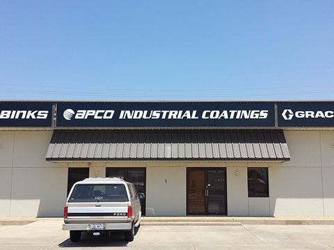 A white truck is parked in front of a building that says apco industrial coatings