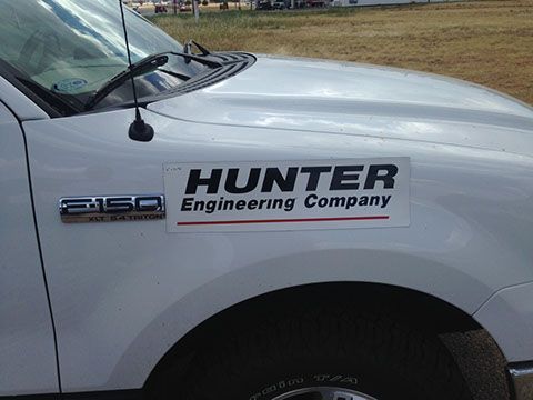 A white truck with a sticker on the hood that says hunter engineering company