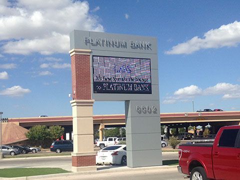 A red truck is parked in front of a platinum bank sign