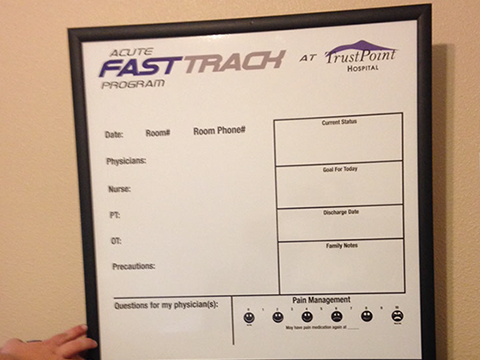 A person is holding a whiteboard that says fasttrach at trustpoint