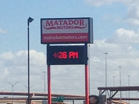 A sign for matador motors shows the time as 4:26 pm
