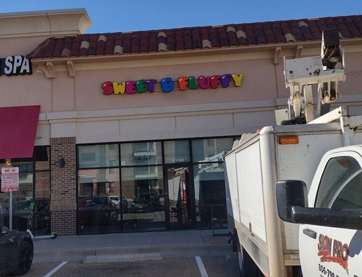 A white truck is parked in front of a building that says sweet & bubbly