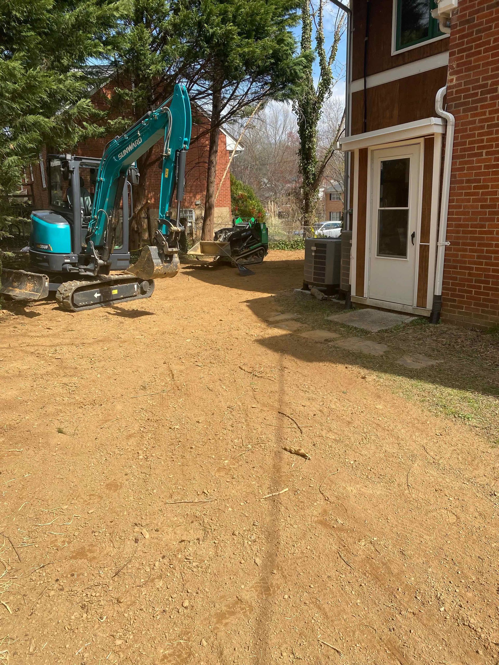 An excavator is parked in front of a brick building