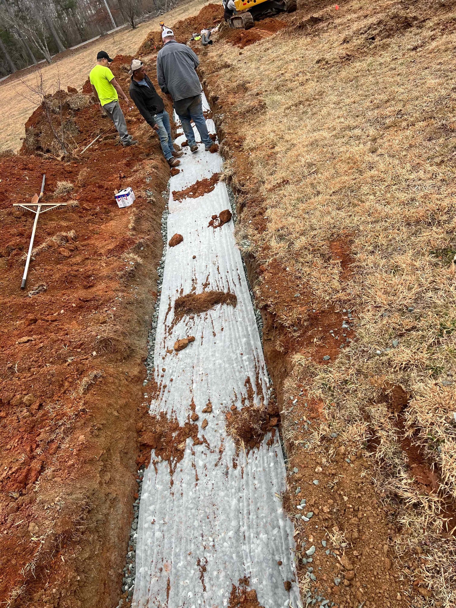 A group of people are working on a drainage system in a field.