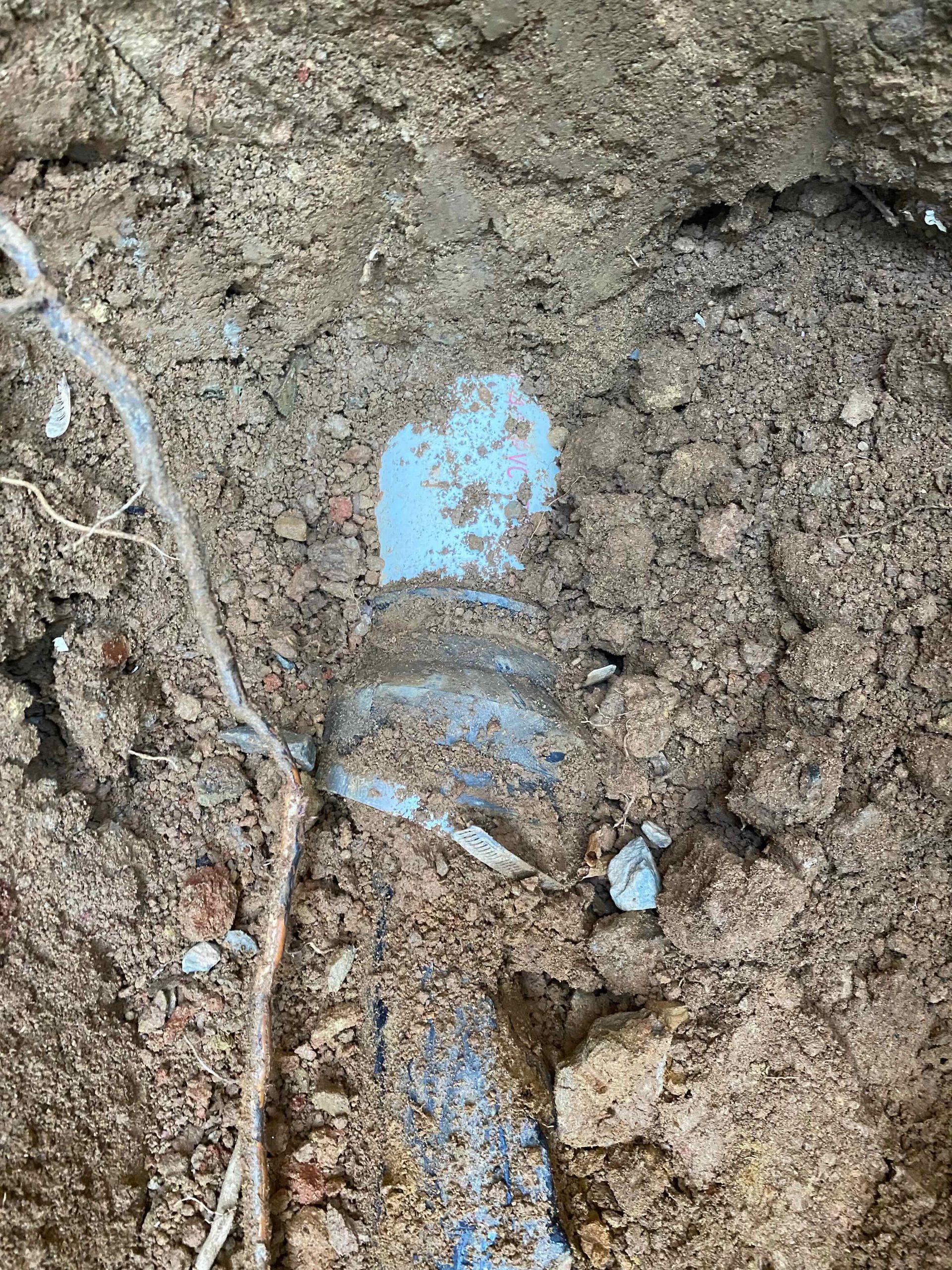 A blue pipe is laying in the dirt.