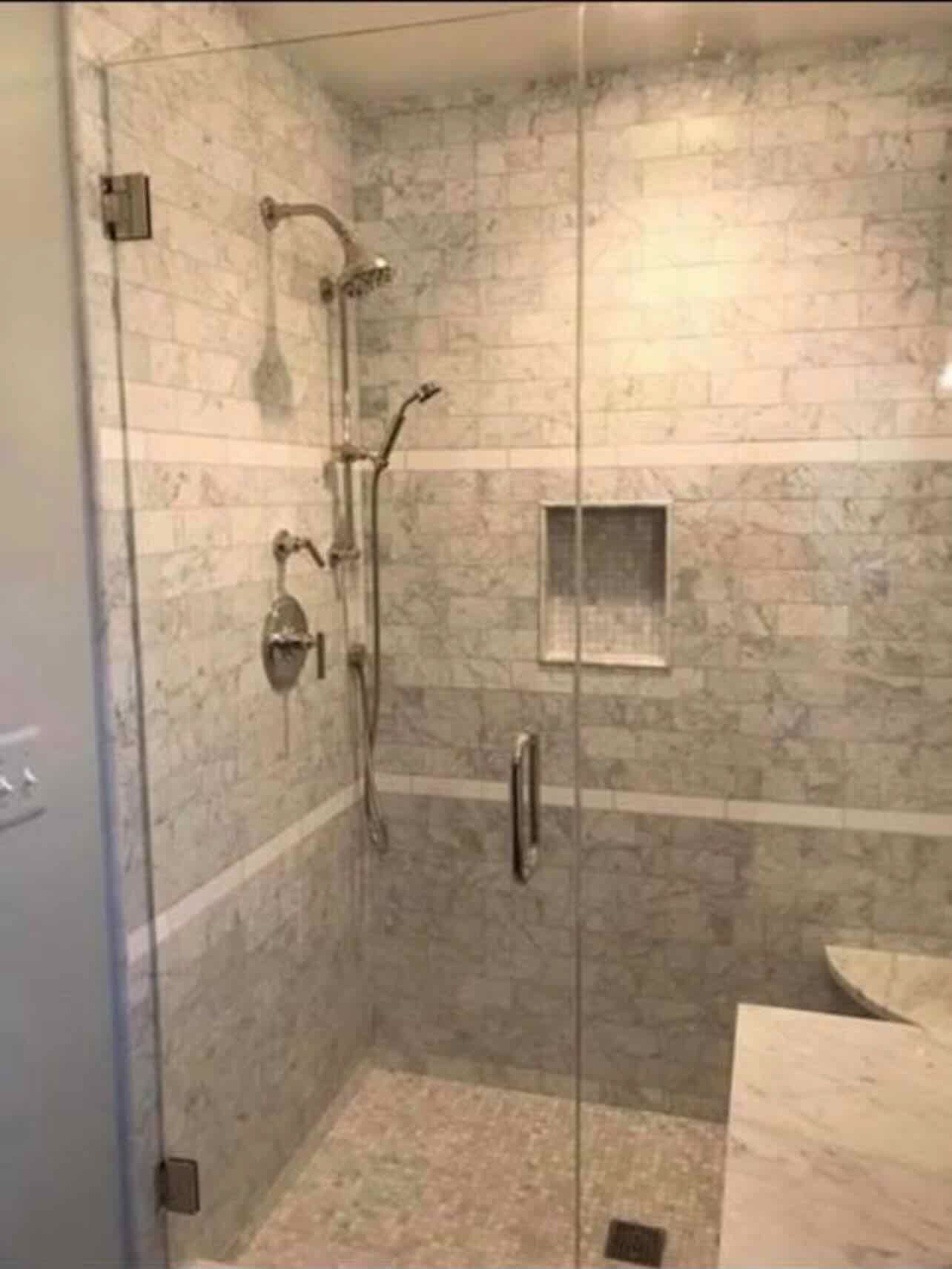A bathroom with a walk in shower with a glass door.