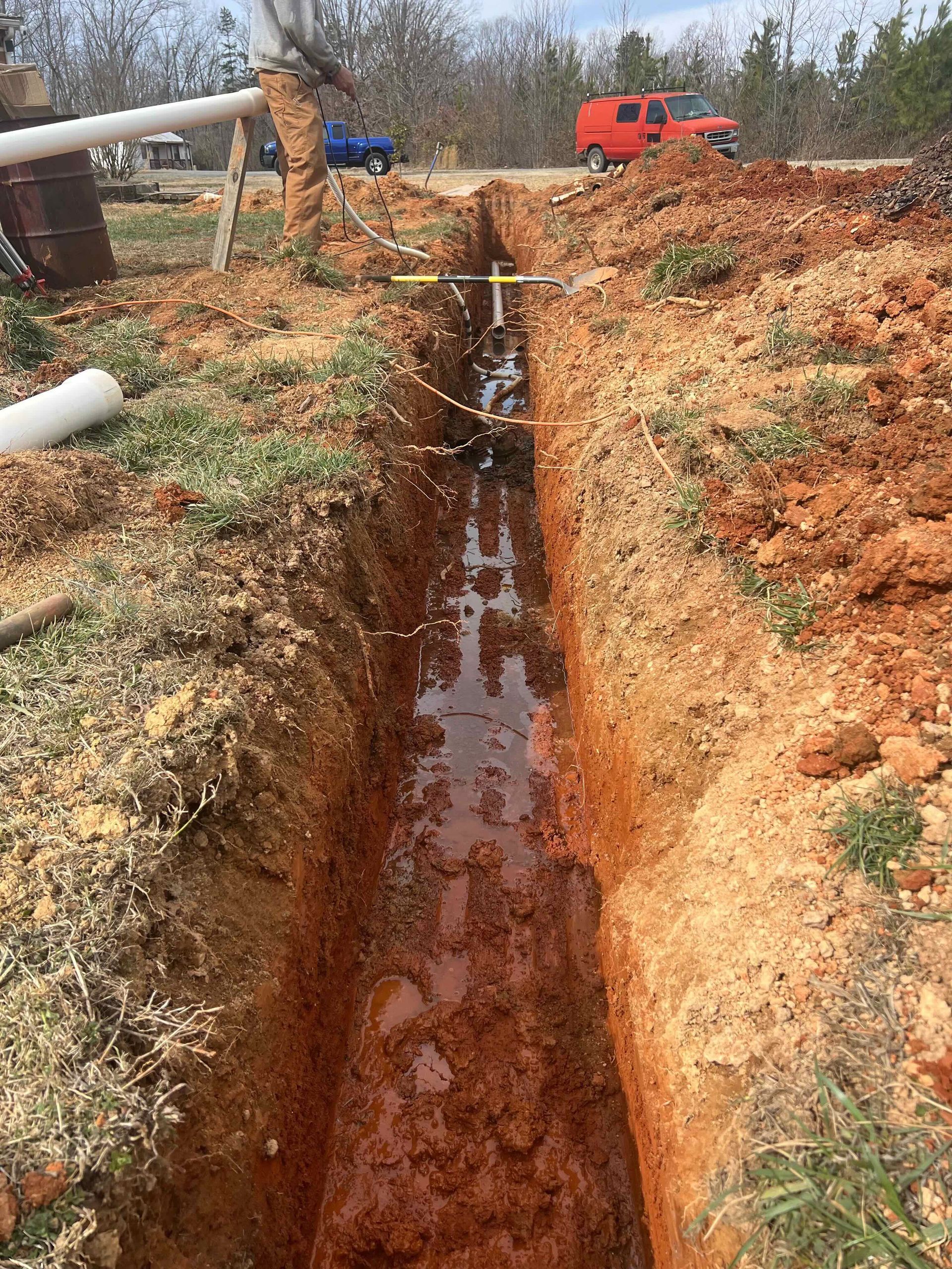 A man is digging a trench in the dirt next to a road.