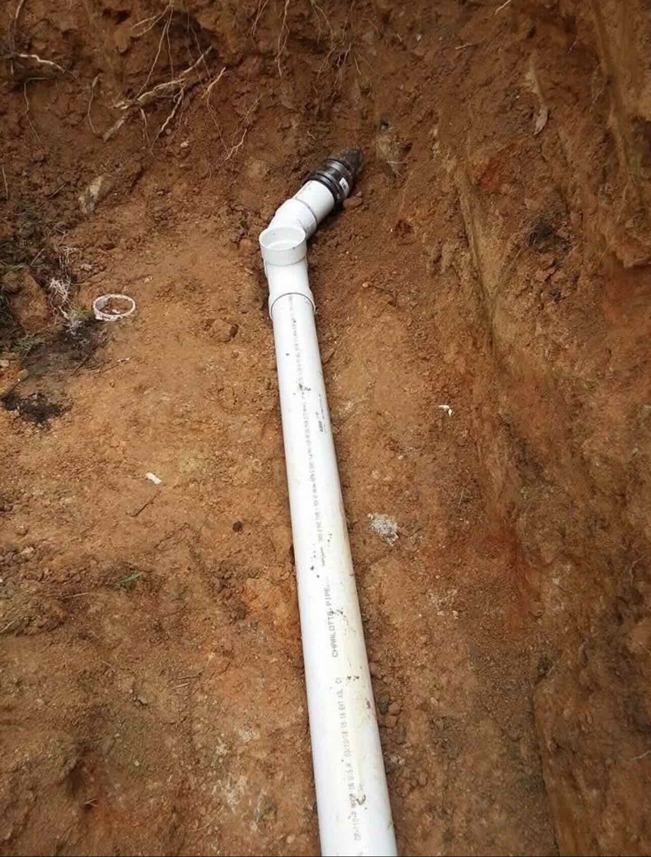 A white pipe is sitting on top of a pile of dirt.