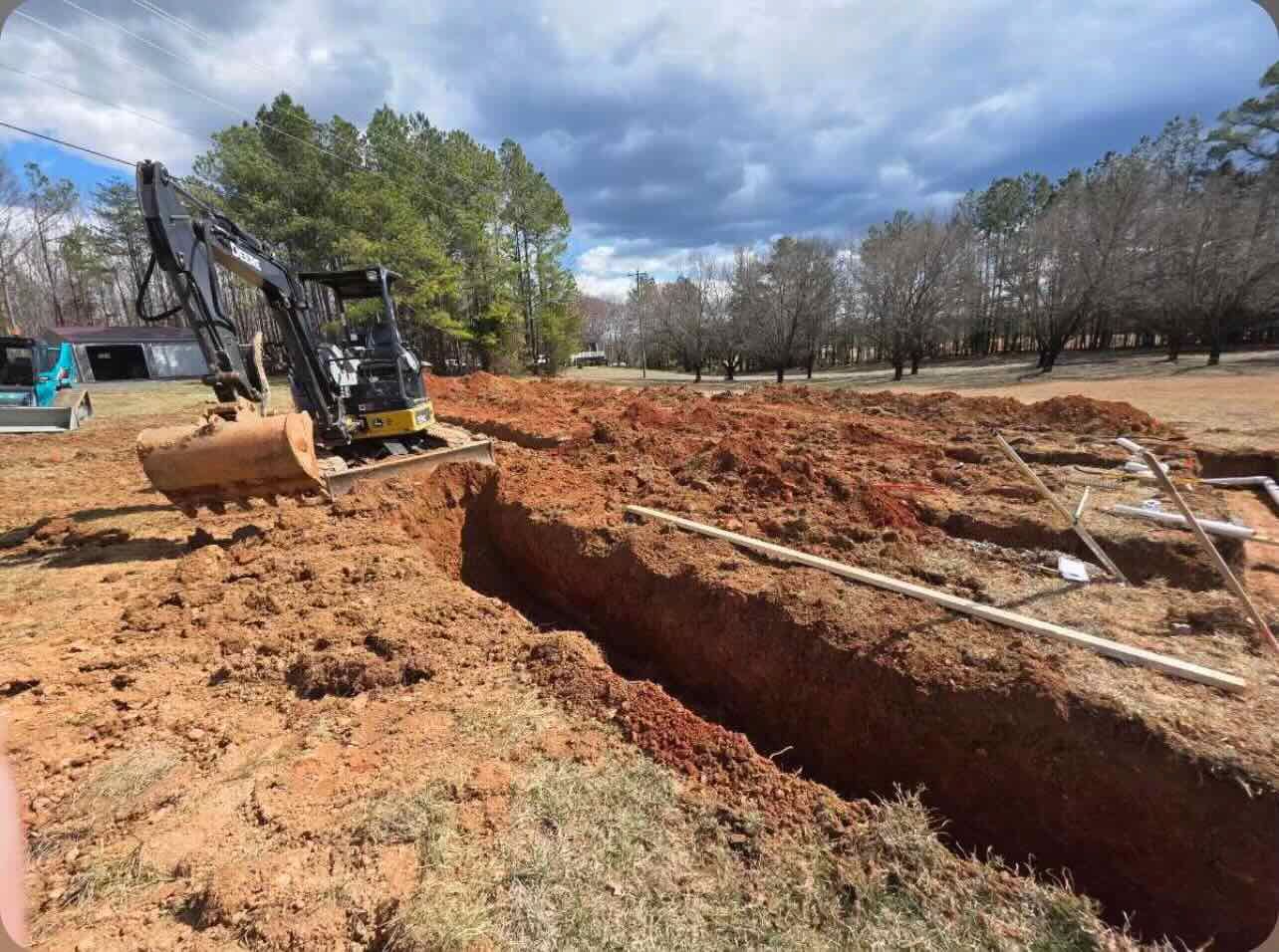 An excavator is digging a hole in the dirt in a field.