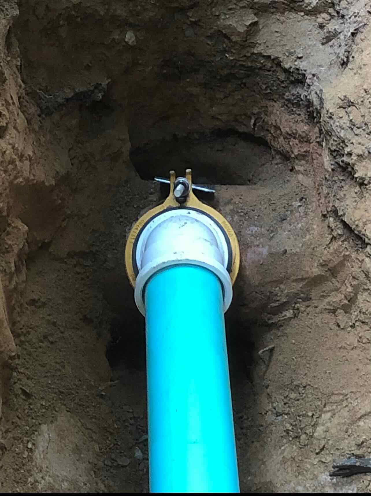 A blue pipe is being installed in a hole in the ground.