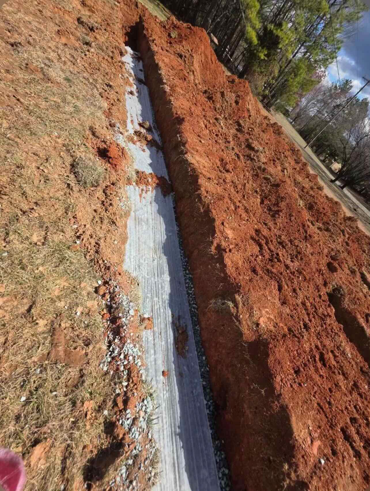 A large pile of dirt is being covered with a white tarp.