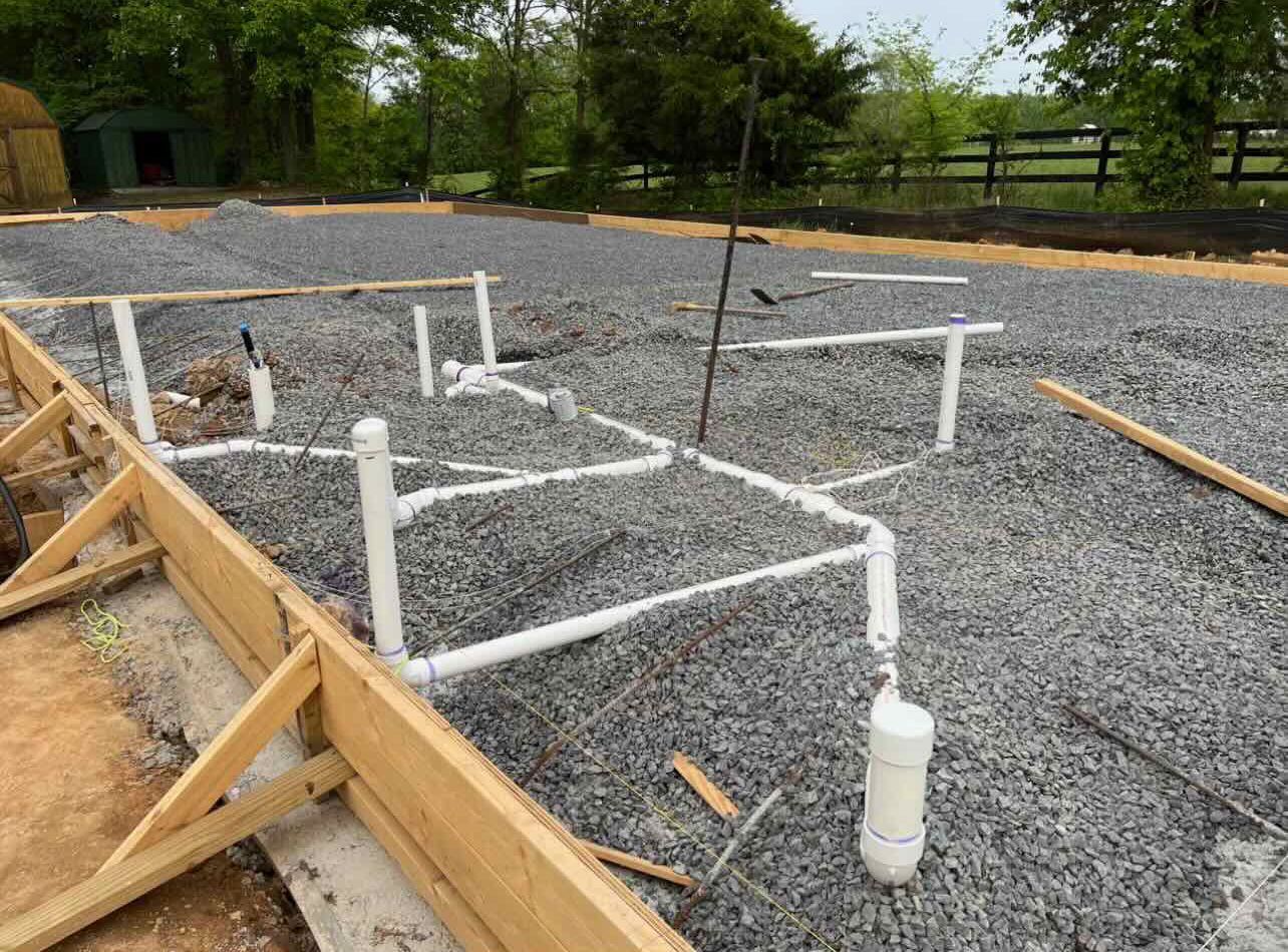 A construction site with a lot of pipes laying on the ground.