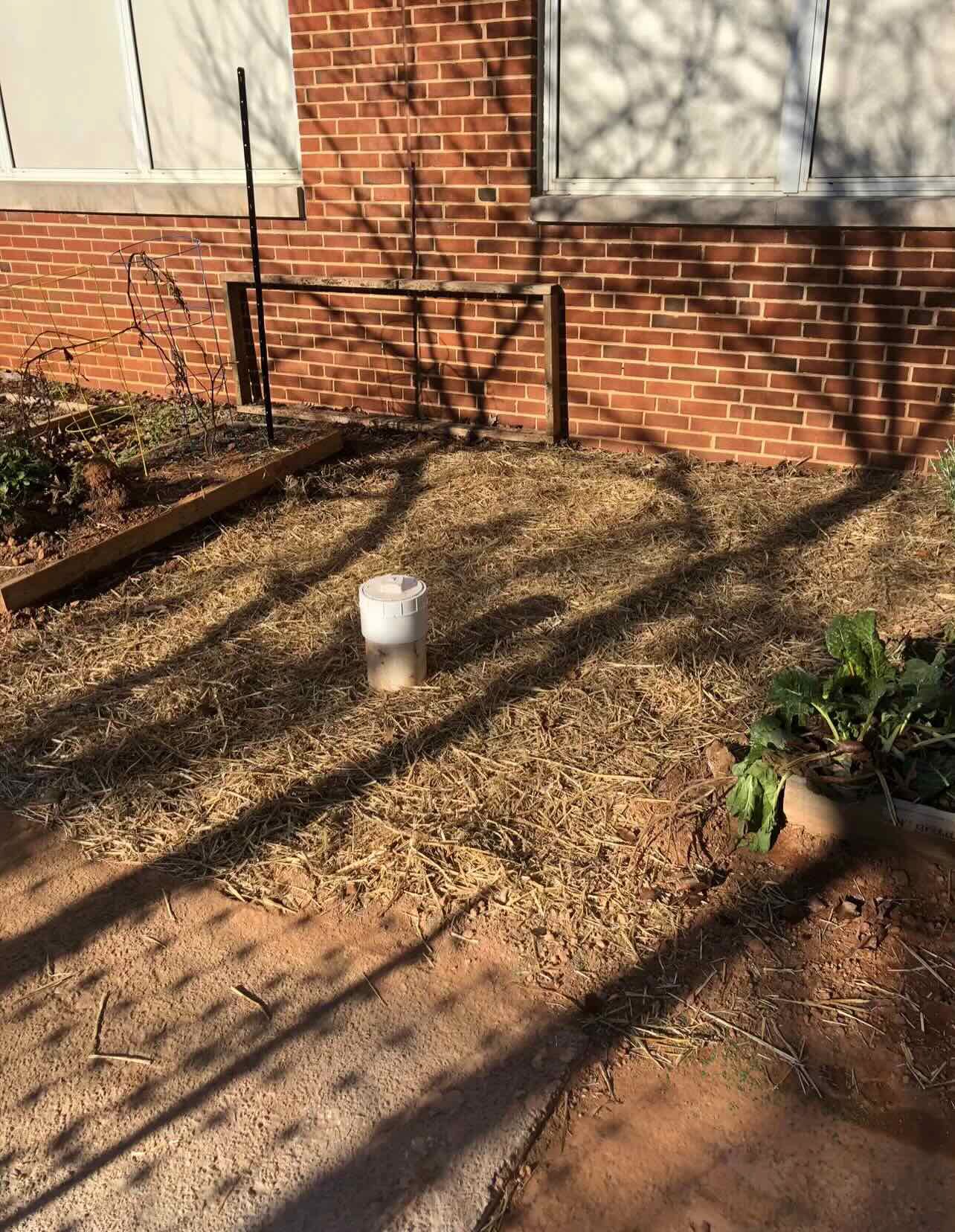 A brick building with a bucket on the ground in front of it.