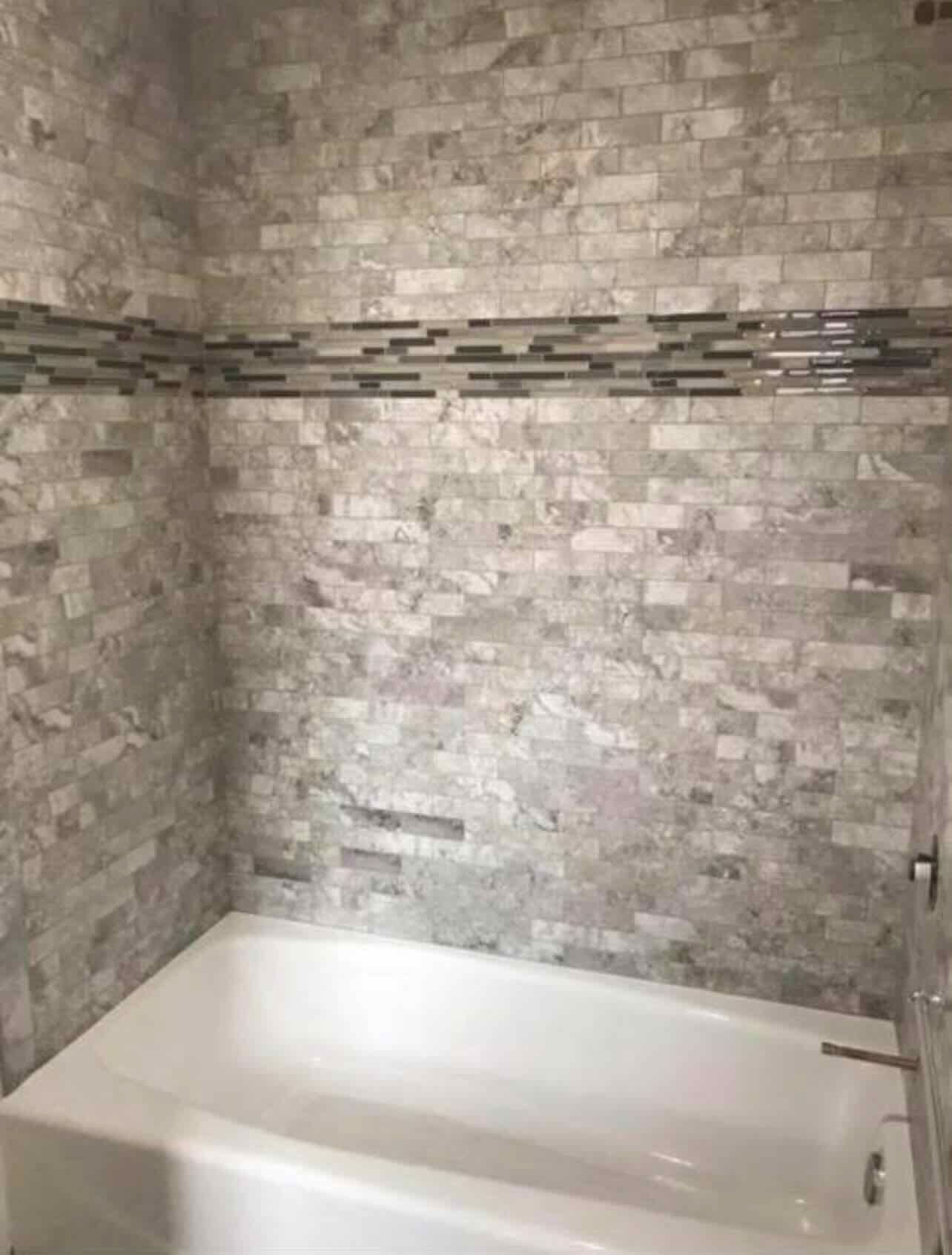There is a bathtub in the bathroom with a brick wall.