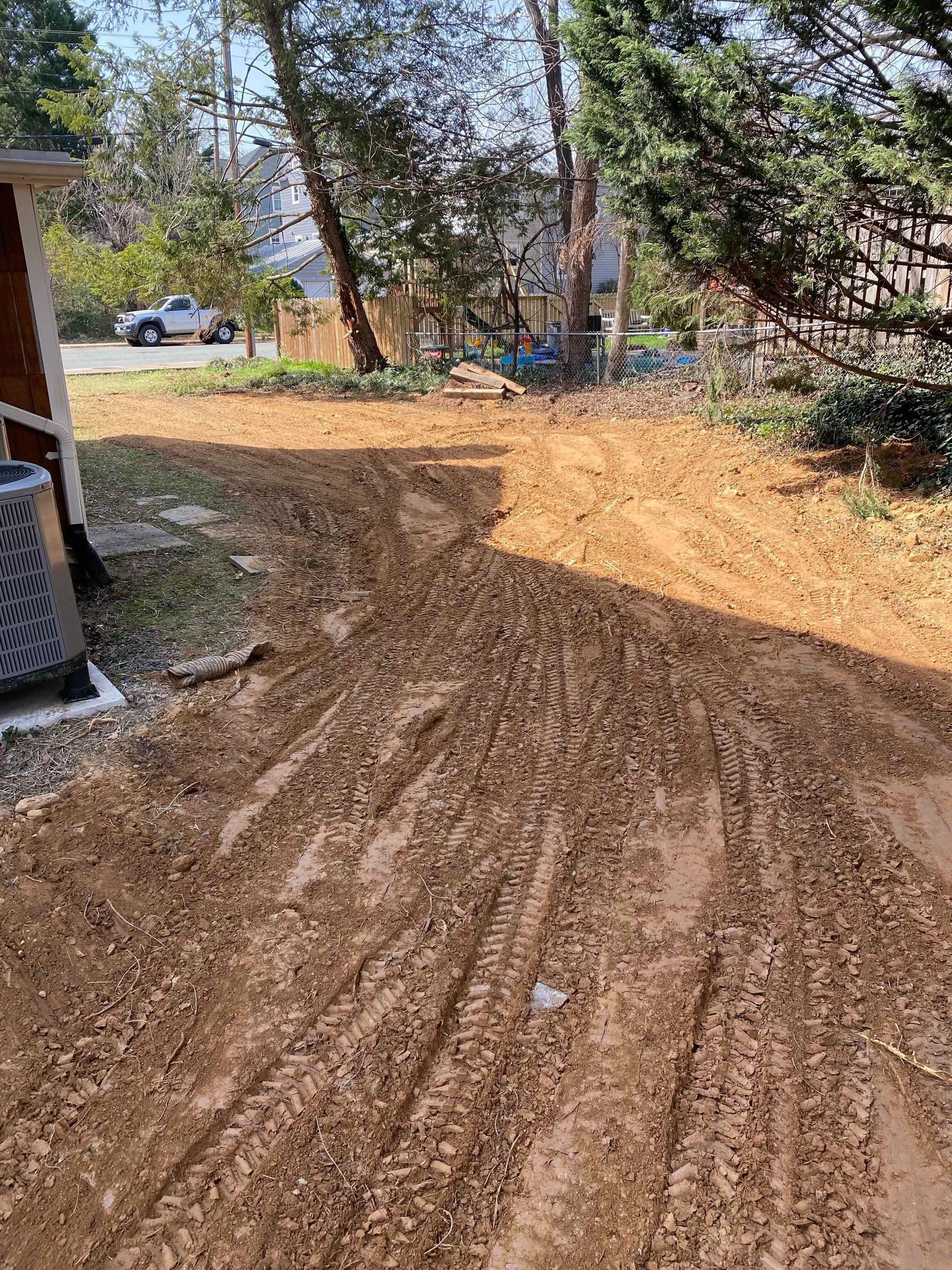 A dirt road leading to a house with trees in the background.