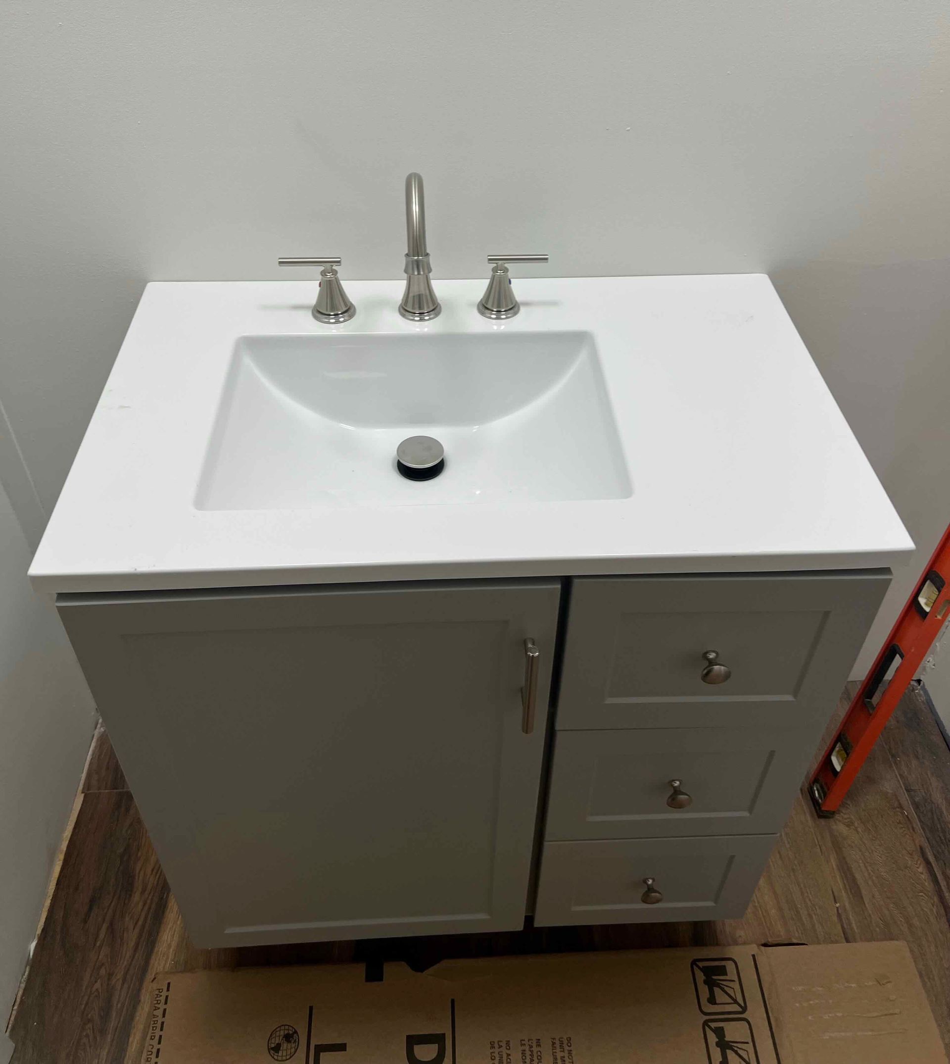 A bathroom sink is sitting on top of a cardboard box.