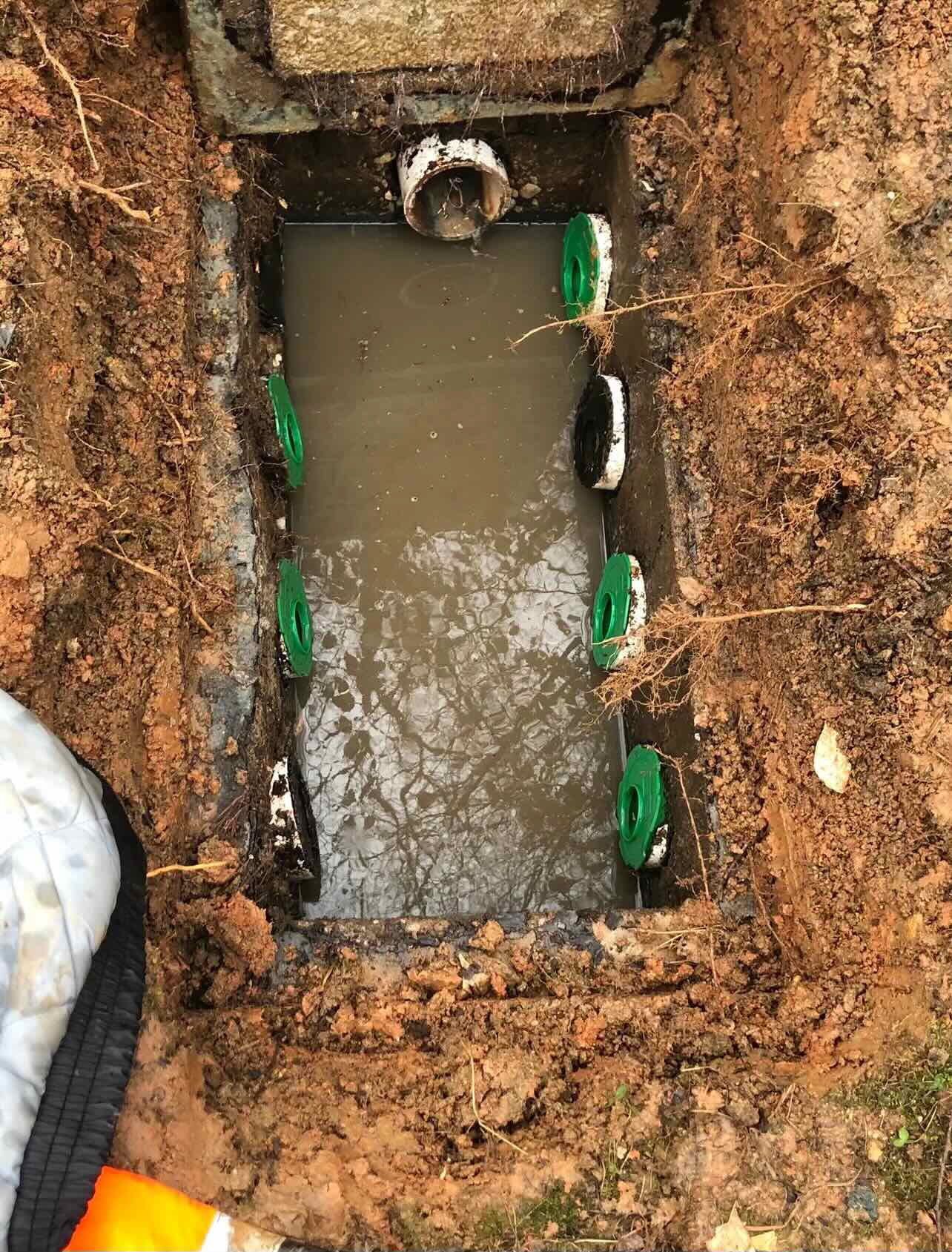 A septic tank is filled with water and is sitting in the dirt.