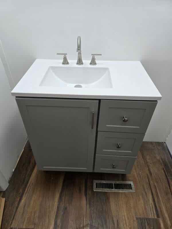 A bathroom vanity with a sink and drawers on a wooden floor.