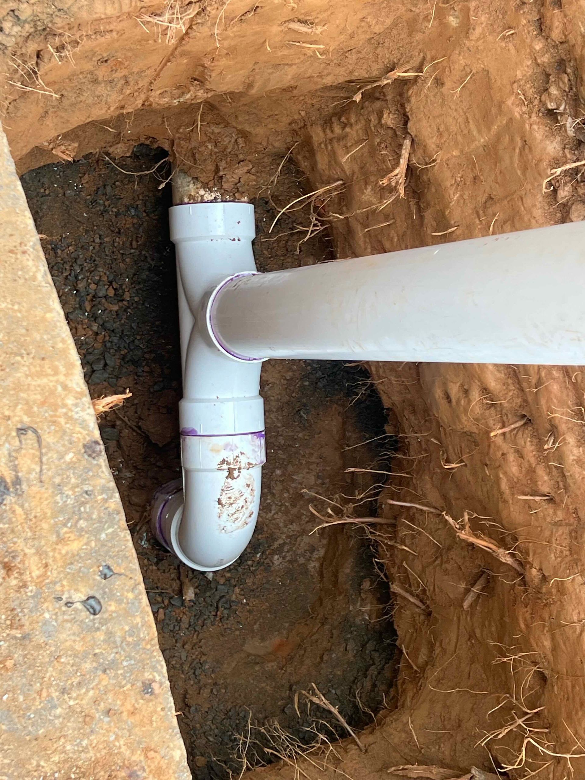 A white pipe is sitting in a hole in the ground.