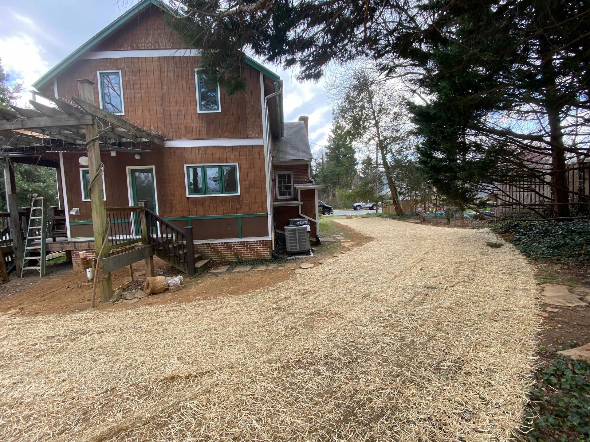 A large wooden house with a gravel driveway in front of it.