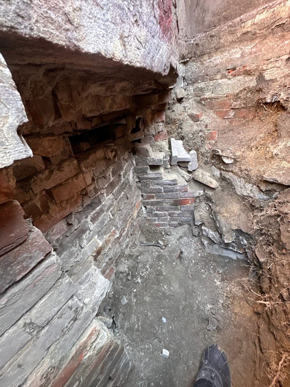 Brick foundation exposed by excavation, showing old brickwork and soil.