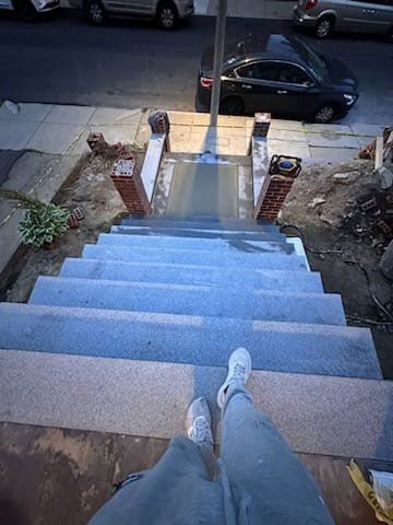 Person standing on newly constructed concrete steps leading up to a building entrance.