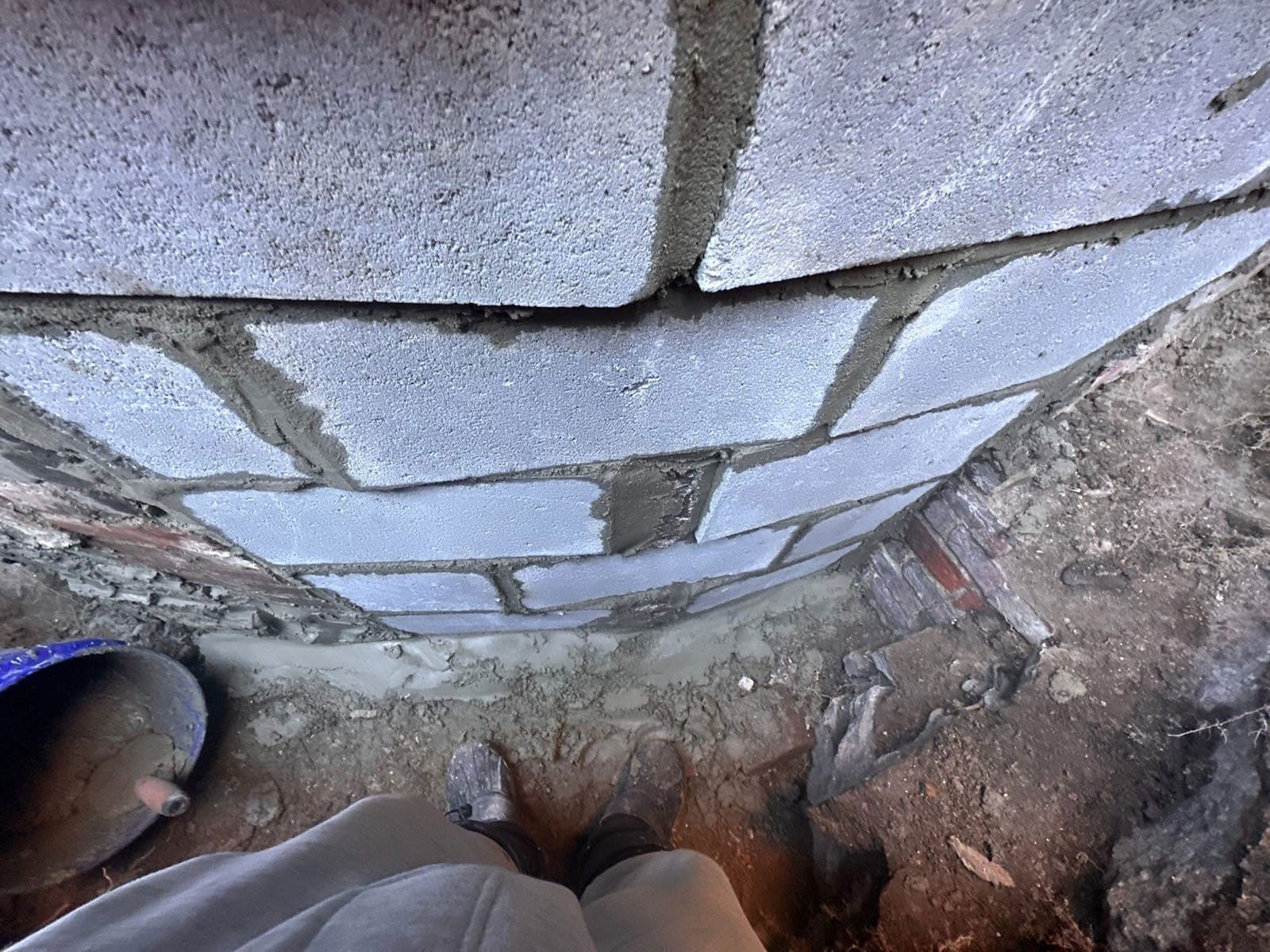 Curved gray cinder block wall under construction; mortar visible.