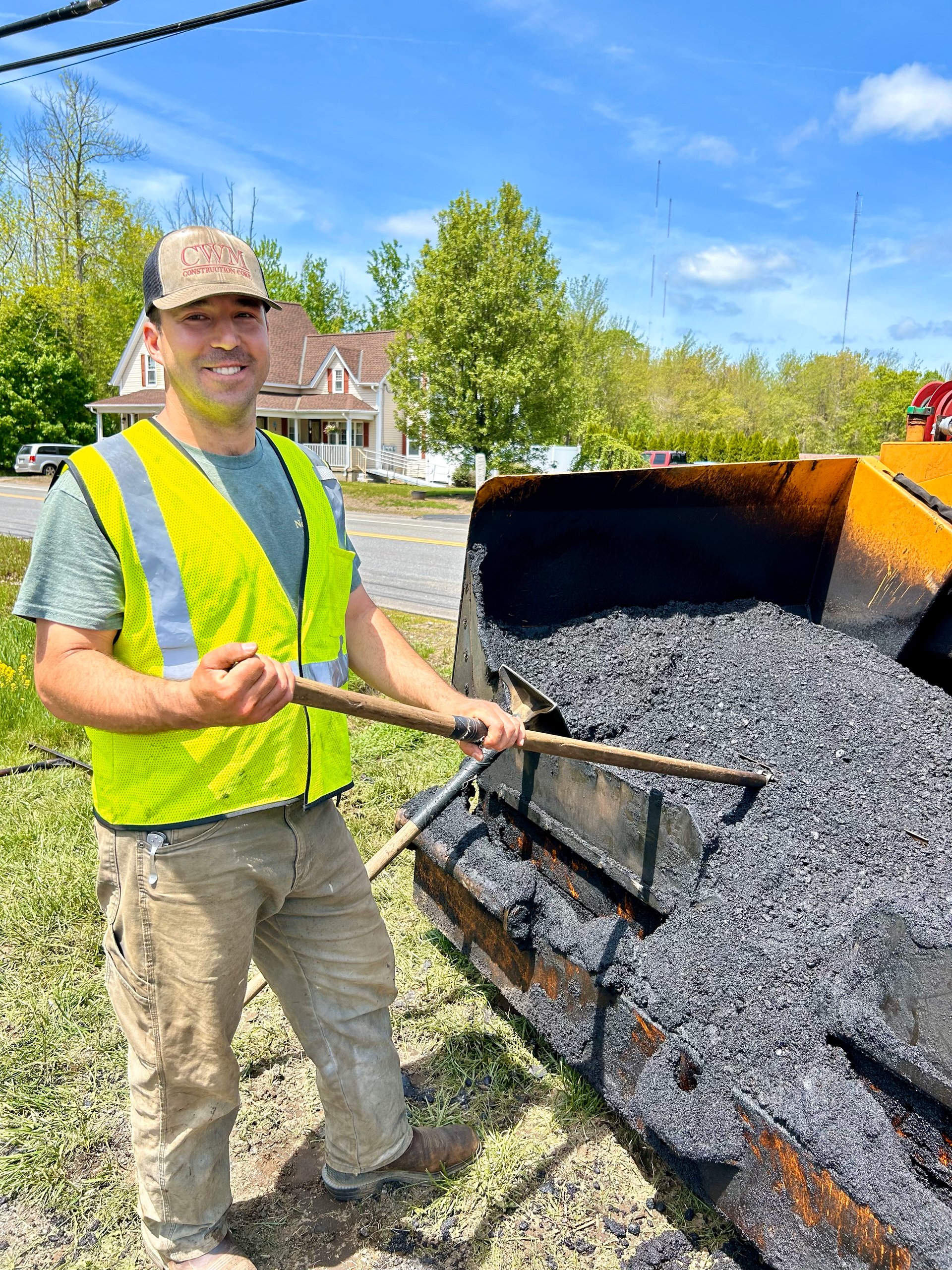A man in a yellow vest is standing next to a bulldozer.