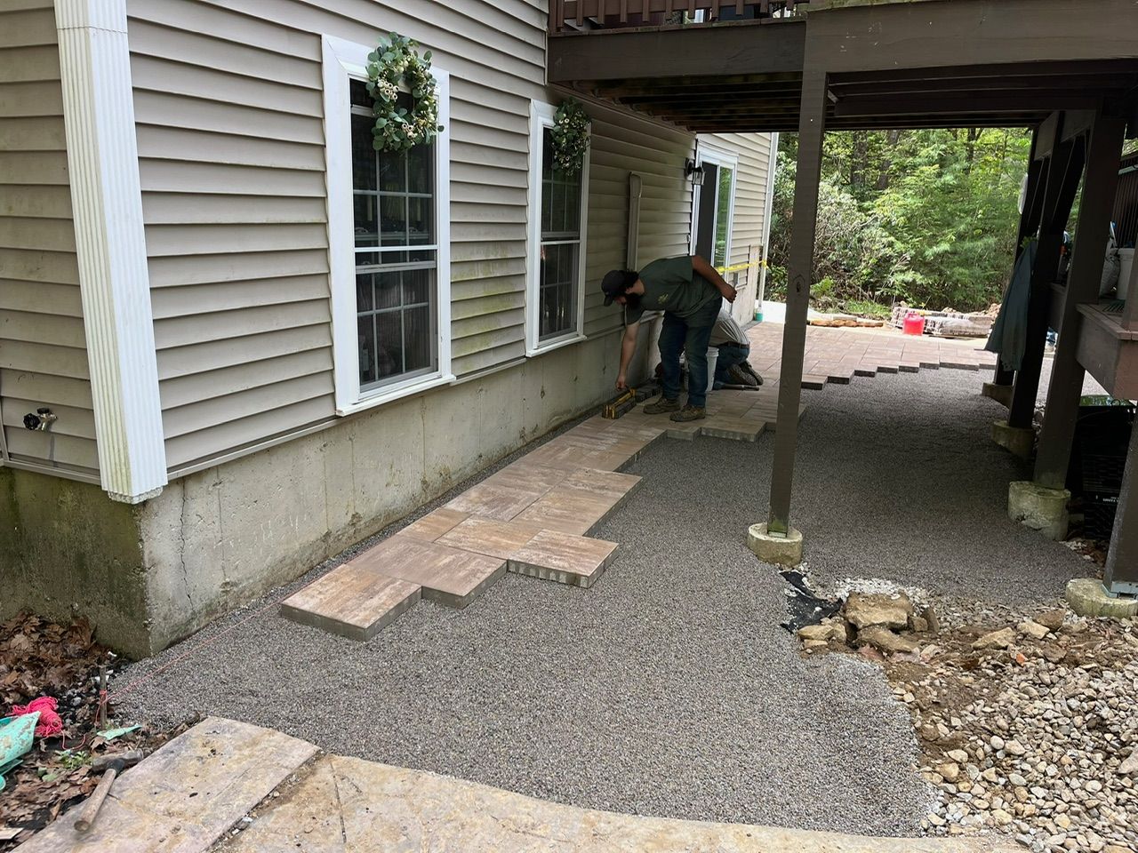 man under the deck laying patio pavers